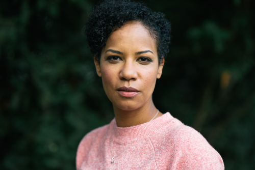 Eine Frau mit rosefarbenem Oberteil schaut in die Kamera.